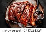 Hot grilled spare ribs from a summer BBQ served on a plate with sauce. Top view.