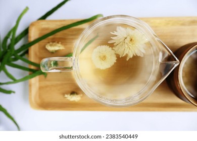 Hot herbal tea made by soaking dried chamomile flowers in hot water in a glass pitcher. Fragrant and light yellow on a wooden tray, white background

 - Powered by Shutterstock