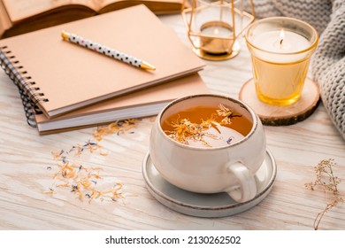 Hot Herbal Tea With Notepad, Candle, Book And Blanket. Cozy And Hygge Lifestyle