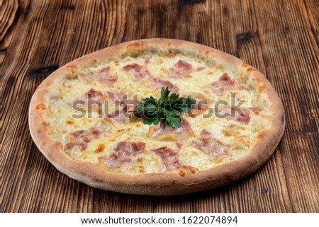 Hot italian pizza with melted cheese and bacon strips on wooden background 