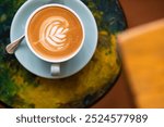 hot latte in a blue coloured cup. with copy space to the side. cup sitting on a marble chair. top down view. with foreground table blur. 