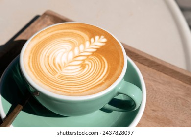 Hot latte coffee with beautiful latte art serve in green color cup