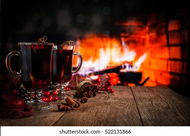 Hot mulled wine in a glass with orange slices, anise and cinnamon sticks on vintage wood table. Fireplace as background. Christmas or winter warming drink. - Powered by Shutterstock