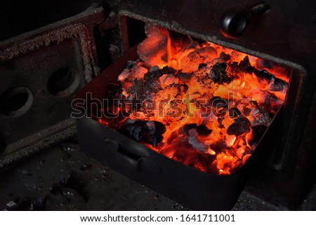 Hot orange coals pulled from the stove. Ash tray with hot ember. Image of the bottom of an old coal stove.