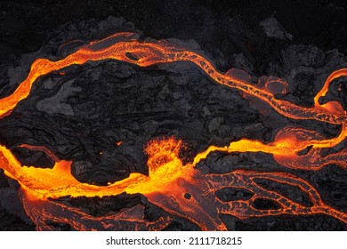 Hot orange and yellow lava rivers flowing coming from an erupting volcano in Iceland from above