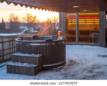 Hot outdoor wooden bath tub  on terrace of private house at winter. Luxury cottage. Finnish sauna.