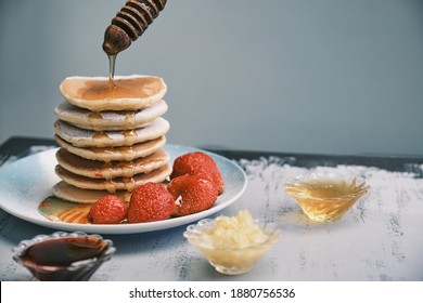 Hot Pancakes With Honey On A Plate. A Delicious Dish For Breakfast. Honey Flows Down From A Wooden Stick On A Dish. Homemade Food. High Quality Photo