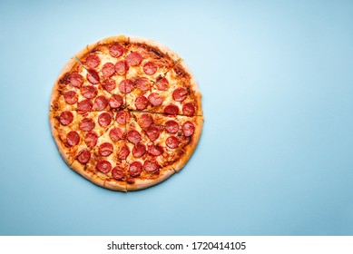 Hot Pepperoni Pizza Sliced On A Blue Table Above View. Delicious Homemade Italian Food. Pizza With Hot Pepperoni And Mozzarella