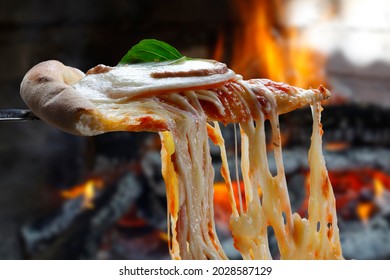Heiße Pizzaausschnitt mit Schmelzkäse mit Holzofen im Hintergrund.