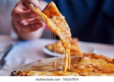 Hot pizza slice with melting cheese.  Lunch or dinner  delicious food italian traditional on wooden table  in side view. Close up Italian pizza with cheese it stick. Selective focus. - Powered by Shutterstock