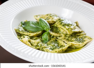 Warme Ravioli mit Spinat serviert in einem weißen Teller mit Pesto-Pause. Traditionelle italienische Küche