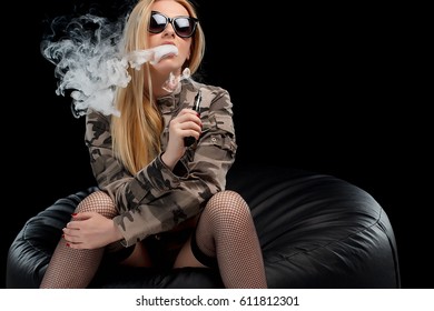 Hot and sexy blonde is sitting and vaping (smoking an e - cigarette). Studio shooting.