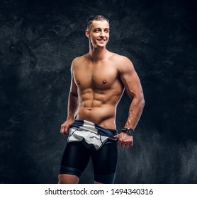 Hot Sexy Fit Man Is Taking Off His Wetsuit In Dark Photo Studio.