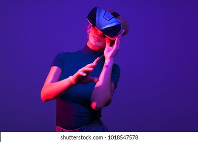 Hot Sexy Woman Wearing A VR Head Set On Blue Background With Red Light From Aside