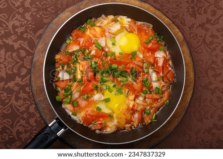 hot shakshuka in a frying pan sprinkled with green onions on a wooden stand. Horizontal photo