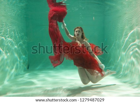 Hot Slim Caucasian Woman Posing Under water in beautiful clothes alone in the deep