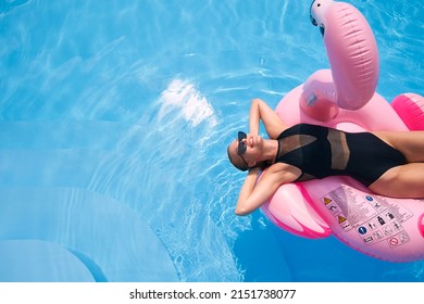 Hot Slim Woman Relaxing On Inflatable Pink Flamingo Float Mattress In Bikini At Swimming Pool. Attractive Fit Girl In Swimwear Lies In The Sun On Floaty. Pretty Female Chilling On Tropical Vacation.