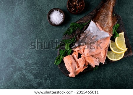 Hot smoked trout fillet on dark green table. Top view. Mockup with copy space
