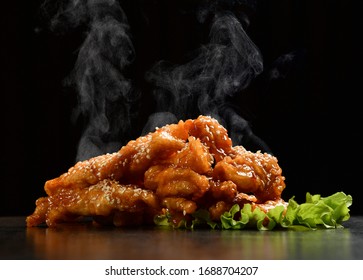 Hot And Spicy Bbq Chicken Wings Strips With With Green Salad Leaf And Steam Smoke On Black Background