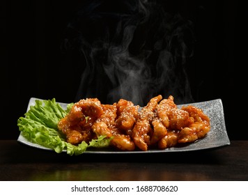 Hot And Spicy Bbq Chicken Wings Strips With With Green Salad Leaf And Steam Smoke On Black Background