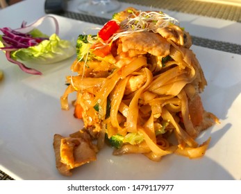 Hot And Spicy Chicken Noodles With Broccoli And Other Vegetables On A White Plate In A Thai Restaurant In Marbella, Spain