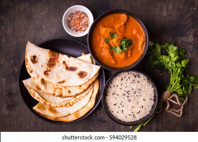 Hot spicy chicken tikka masala in bowl. Chicken curry with rice, indian naan butter bread, spices, herbs. Traditional Indian/British dish, popular indian curry in UK. Top view. Indian food. Close-up 