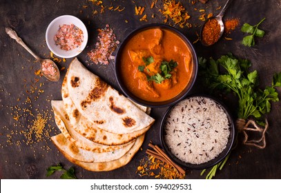 Hot spicy chicken tikka masala in bowl. Chicken curry with rice, indian naan butter bread, spices, herbs. Traditional Indian/British dish, popular indian curry in UK. Top view. Indian food. Close-up 