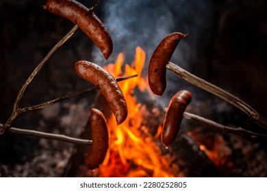 Hot and spicy sausage on stick roasted on bonfire in the summer evening