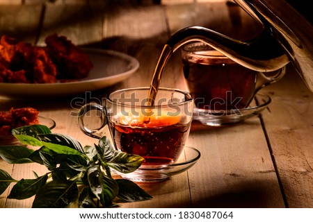 Hot steaming black tea in  a cup on a  rustic background 