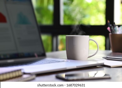 A Hot And Steaming Cup Of Coffee On A Desk With Laptop And Gadget When Work From Home