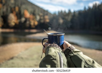 hot steaming cup of coffee or tea in traveler hands. Seasonal, morning coffee, sunday relax after trekking path concept