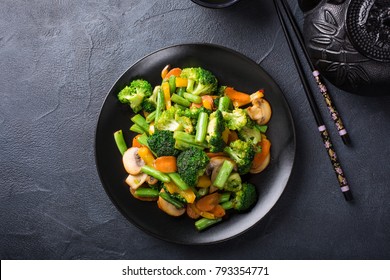 Verdure saltate in padella calda sul piatto nero. Concetto di cibo asiatico sano con spazio copia.