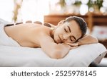 Hot stone massage, relax and woman in spa for massage, peace or stress relief. Beauty, rocks on back of person in salon for body therapy and wellness treatment or healthy detox with eyes closed