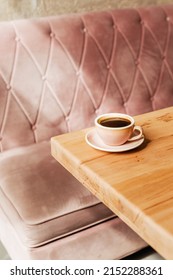 Hot strong black coffee on a wooden table. Delicious Americano in a pink ceramic cup in a coffee shop with space for text