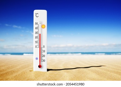 Hot summer day. Celsius scale thermometer in the sand. Ambient temperature plus 30 degrees 