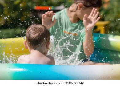 A Hot Summer Day. Children Swim And Splash In The Pool. A Happy Little Boy Smiles At The Camera. Splashes Of Water Are Flying In All Directions. The Concept Of Summer Holidays With Children.