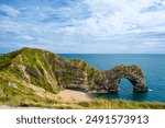 Hot summer day at Durdle Door. Durdle Door limestone arch on the Jurassic Coast in Dorset.Natural landmark.Summer holidays England. Crowded beach, people are spending summer weekend in English seaside