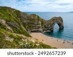 Hot summer day at Durdle Door. Durdle Door limestone arch on the Jurassic Coast in Dorset.Natural landmark.Summer holidays England. Crowded beach, people are spending summer weekend in English seaside