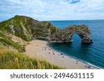 Hot summer day at Durdle Door. Durdle Door limestone arch on the Jurassic Coast in Dorset.Natural landmark.Summer holidays England. Crowded beach, people are spending summer weekend in English seaside