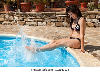 Hot summer day with a woman splashing with water at the poolside - Powered by Shutterstock