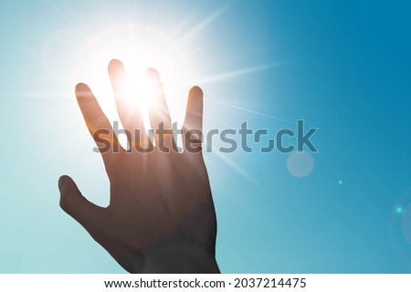 Hot summer sunlight rays pouring through a human hand. Hand covering light