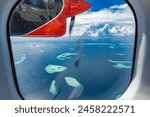 Hot summer sunny day in Maldives islands, view from seaplane window. Dream wanderlust tourism vacation background. Indian ocean atolls, coral reefs, shallow sea bay and luxury resort islands lagoons