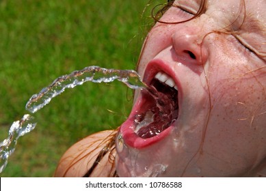 Hot and sweating young girl seeking refreshment from water fountain
