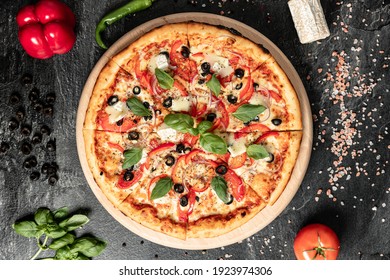 Hot tasty traditional italian pizza with salami, meat, cheese, tomatoes greens on a dark background - Powered by Shutterstock