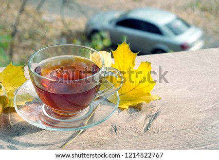 Hot tea for cold autumn. A cup of hot tea, and maple leaves on the windowsill. Cup with tea over autumn background.