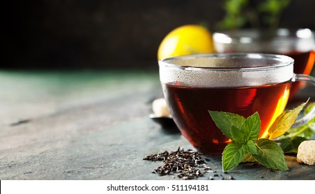 Hot tea cup with mint and sugar on rustic background