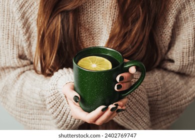 Hot tea in a mug. Woman holding mug of lemon tea. Cold winter relax background. Woolen sweater warm clothing. Long hair girl. Cozy atmosphere. Female hands holding tea. - Powered by Shutterstock