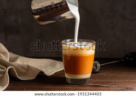 Hot Thai tea latte with milk froth in the glass. Pouring milk froth to the glass. 