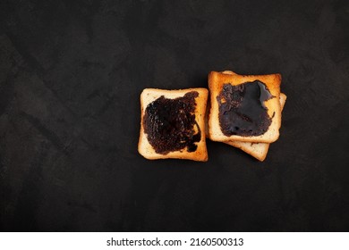 Hot toasted bread for breakfast. Roasted Aussie savory toasts with vegemite spread. Vegemite is a very popular yeast based spread in Australia. Dark background, copy space.