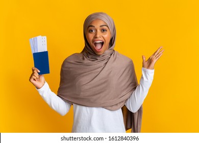 Hot Tours Concept. Overjoyed Black Muslim Girl Holding Passport With Tickets And Emotionally Rejoicing Success, Yellow Background With Copy Space